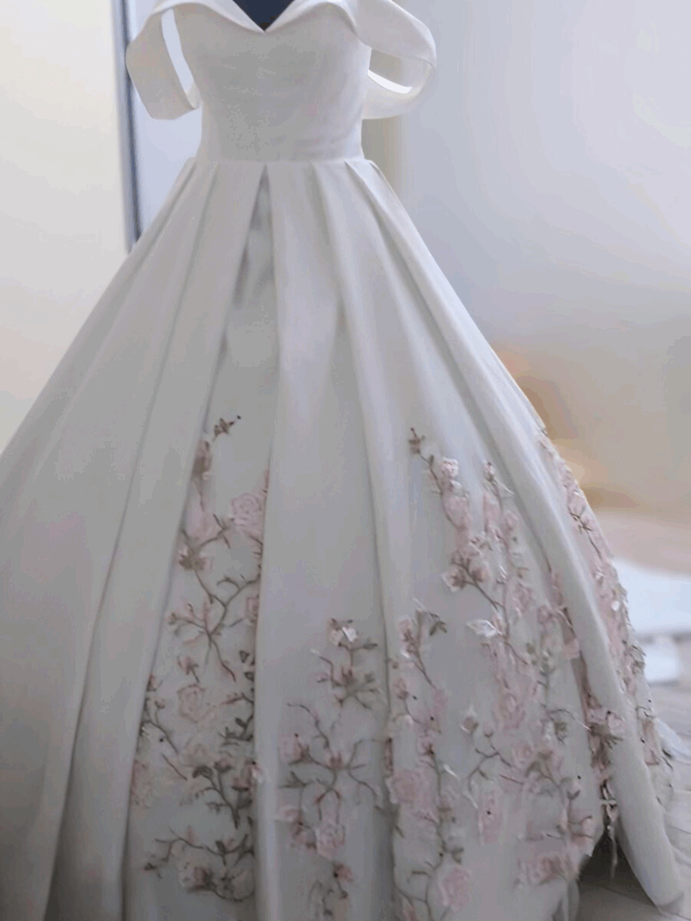 Pose artisanale de dentelle florale pastel sur satin laiteux dans l’atelier de couture Laura Queen Création.
