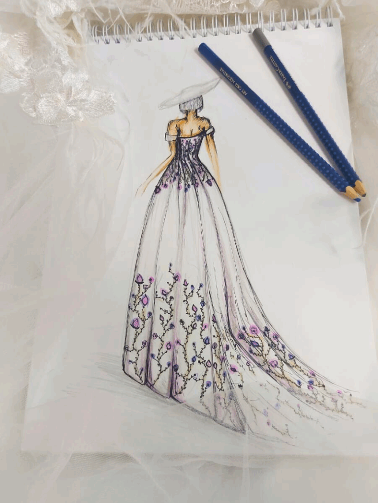 Pose artisanale de dentelle florale pastel sur satin laiteux dans l’atelier de couture Laura Queen Création.